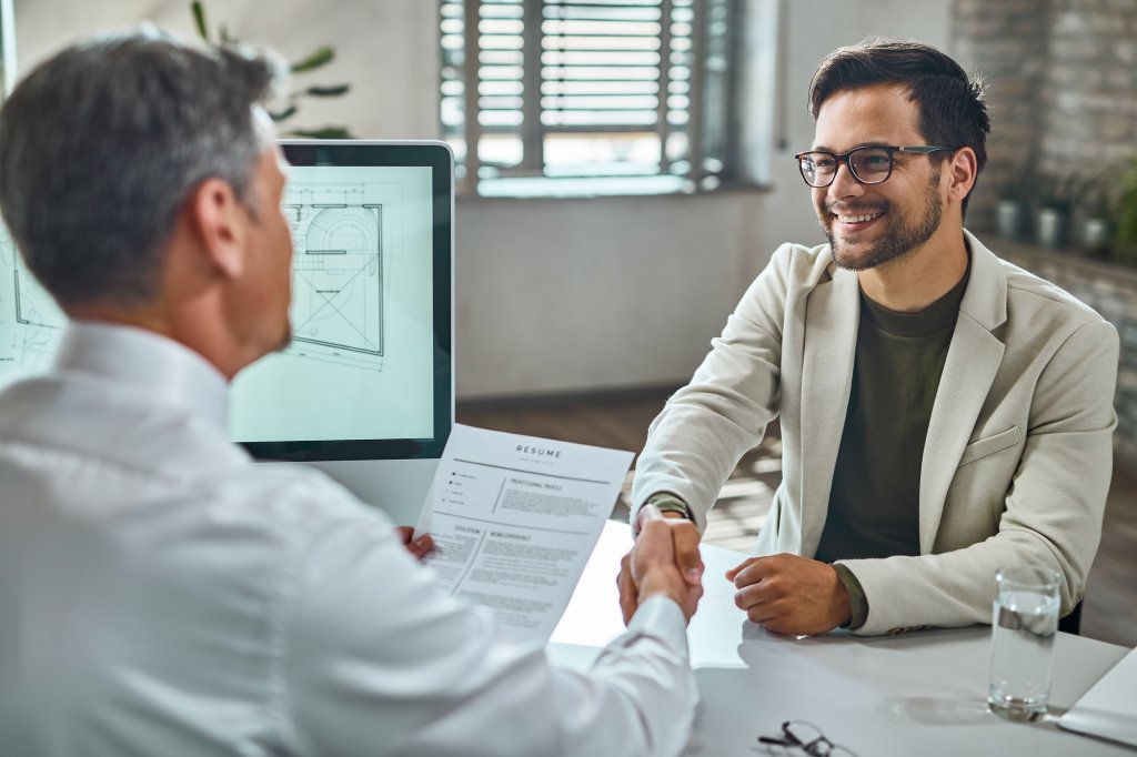 Happy male candidate greeting a businessman on a job interview in the office.